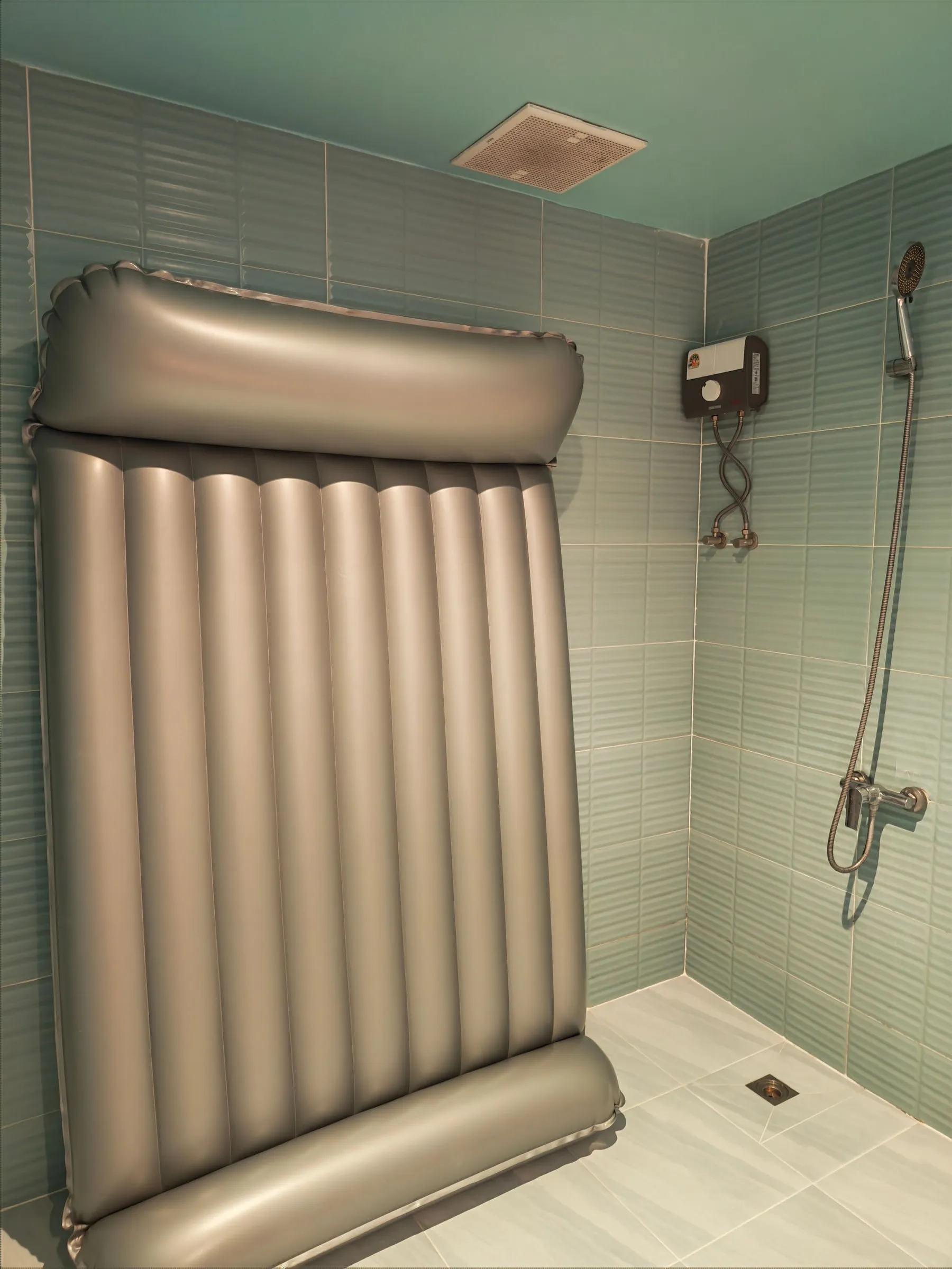 The tiled wet area of a J-SPOT room: the inflatable nuru mat and a hand shower