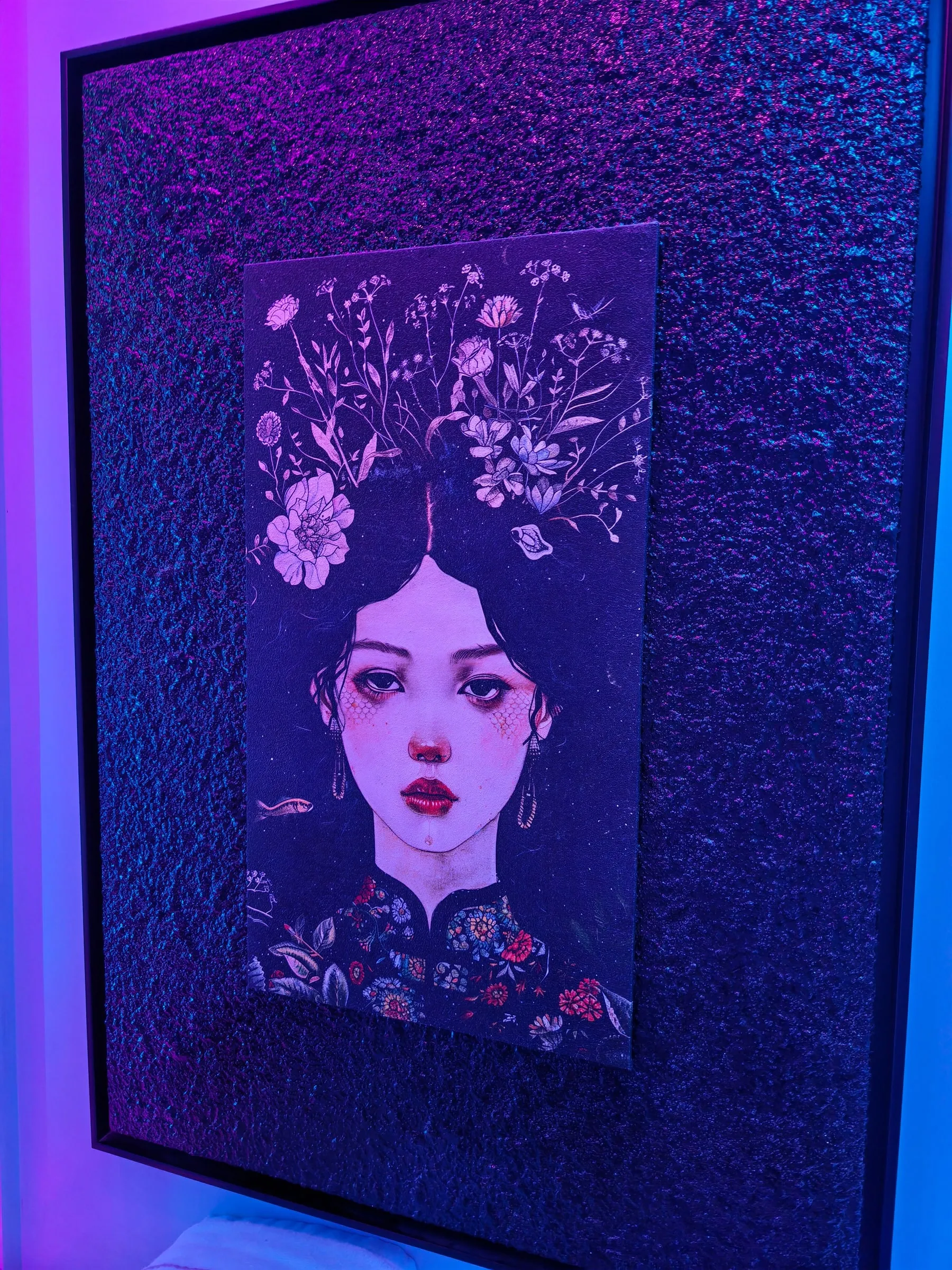 J-SPOTの絵。花を頭に飾った女性のイラストが、質感のある紫の壁に掛かっています